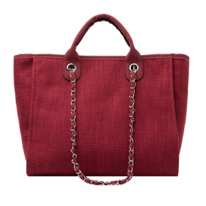 Detalle macro del bolso tote de tejido burdeos con textura y correa de cadena plata