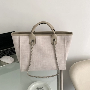 Bolso tote de lona tejida beige con adornos de cuero marrón y correas de cadena