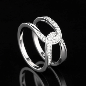 Macro detail of overlapping silver wave bands with pave-set zircon stones on a dark background