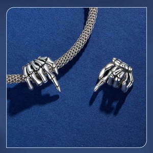 Close-up of gothic S925 silver skeleton hand charm on a metal mesh bracelet