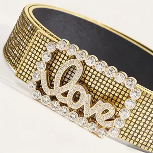 Dettaglio macro della fibbia con strass e scritta Love su cintura in pelle con borchie oro