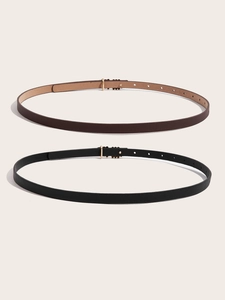 Detail view of thin PU leather belts in black and brown with golden metal pin buckles
