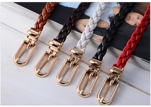Close-up of five thin woven leather belts in brown and white with gold buckles