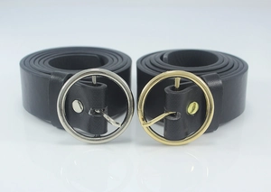 Close-up of black leather belts with classic gold and silver circular metal buckles