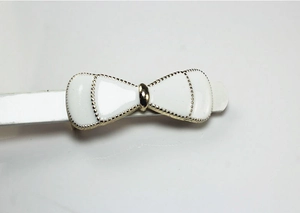 Detailed macro view of white enamel bow belt buckle with gold trim and tiny dot patterns