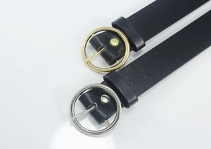 Close-up of black leather belts with gold and silver round metal buckles for women