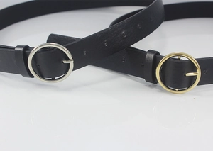 Close-up of thin black leather belt featuring gold and silver round pin buckle details