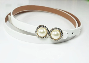 Close-up of elegant white leather belt featuring a pearl and rhinestone encrusted buckle
