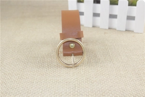 Close-up of brown faux leather belt featuring a classic golden round metal buckle detail