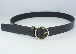 Detail of minimalist black leather belt featuring a polished golden round metal buckle