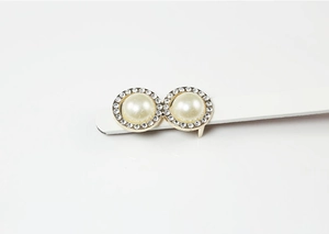 Close-up of pearl and rhinestone buckle detail on a white patent leather belt