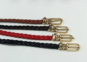 Detail of four colorful woven waist belts with polished golden metal buckles for women