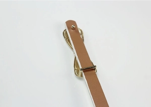 Detailed close-up of brown leather belt with glossy gold metal buckle and studs