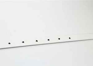 Detailed close-up of a white patent leather belt featuring neat adjustment holes and texture