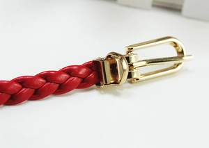 Macro shot of red braided leather belt with a polished gold metal pin buckle closure