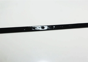 Detailed macro view of black patent leather belt holes with glossy reflective finish