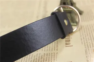 Close-up of black leather belt with a round golden metal pin buckle and rivet