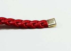 Close-up of red woven waist belt featuring a polished golden rectangular metal tip