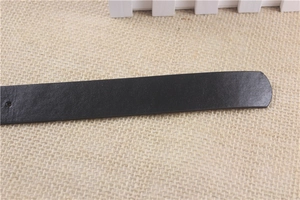 Detail shot of black leather belt tail showing fine grain texture and rounded tip