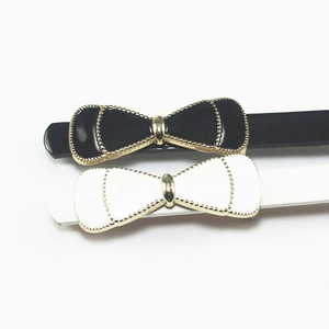 Set of black and white bow hair clips with gold beaded edges on a white background
