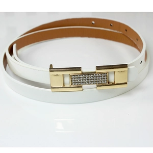 Ceinture fine blanche pour femmes avec boucle en H dorée et strass sur une surface blanche