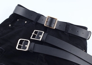 Detailed close-up of three black leather belts with gold and silver geometric buckles