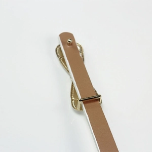 Tan slim patent leather belt for women featuring a gold buckle and bow detail decoration