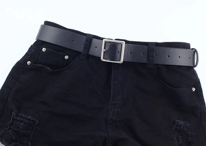 Close-up of a minimalist black leather belt with silver square buckle on denim shorts