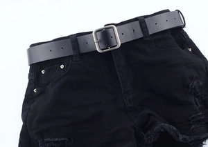 Detail of minimalist black leather belt with silver square buckle on distressed denim