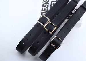 Macro view of black leather belts with square gold and silver buckles on white surface