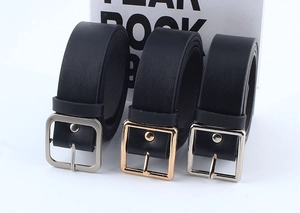 Detailed close-up of classic black leather belts with brushed silver and gold buckles