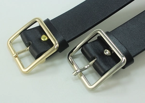 Close-up of black leather belts with gold and silver square metal buckles detail