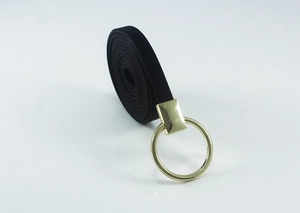 Détail d'une fine ceinture noire montrant une boucle ronde dorée et le matériau souple