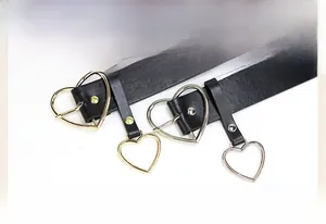 Detail of black leather belt with heart-shaped buckle and matching gold or silver pendant