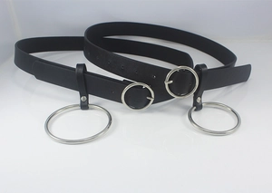Detail of black faux leather belts with silver metal circle buckle and punk style hanging ring