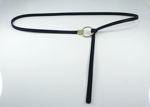 Détail d'une fine ceinture en cuir noir avec boucle ronde dorée nouée avec élégance