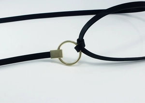 Gros plan sur une fine ceinture noire en cuir avec boucle ronde dorée et détails polis