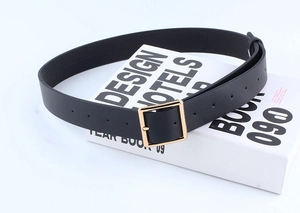 Close-up of black faux leather belt with a polished gold square buckle detail