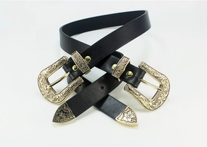 Detail of vintage double-buckle belts with intricate floral gold carvings on black leather