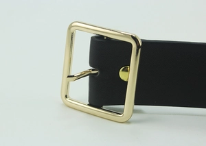 Close-up of classic square gold pin buckle on premium black leather belt with fine texture