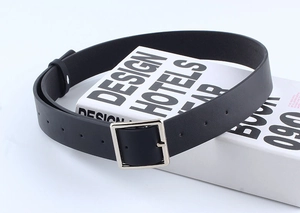 Close-up of classic black leather belt with a polished silver square buckle on a book