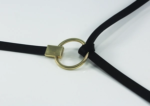 Gros plan sur la boucle ronde dorée et le passant sur une fine ceinture en cuir noir