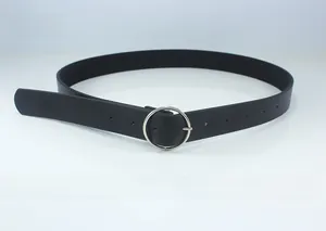 Detail of minimalist thin black leather belt featuring a polished silver metal round buckle