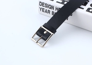 Detail of black leather belt featuring a polished silver square metal buckle and smooth edges