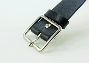 Detailed macro view of the silver square metal buckle and black leather strap texture