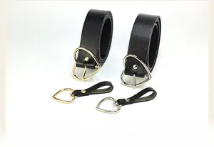 Close-up of black leather belts featuring heart-shaped gold and silver metal buckles