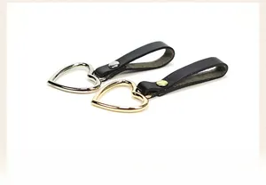 Detail of gold and silver heart pendants with rivets on black leather strap straps