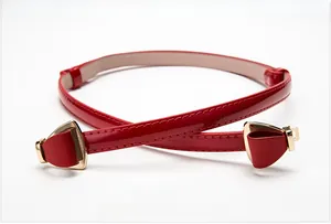 Détail d'une ceinture en cuir verni rouge avec boucle dorée en nœud pour robes femmes
