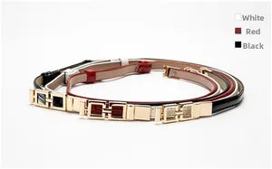 Detailed view of glossy skinny belts in white, red and black with gold square metal buckles