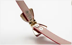 Détail d'une ceinture en cuir rouge pour femme avec boucle dorée en nœud